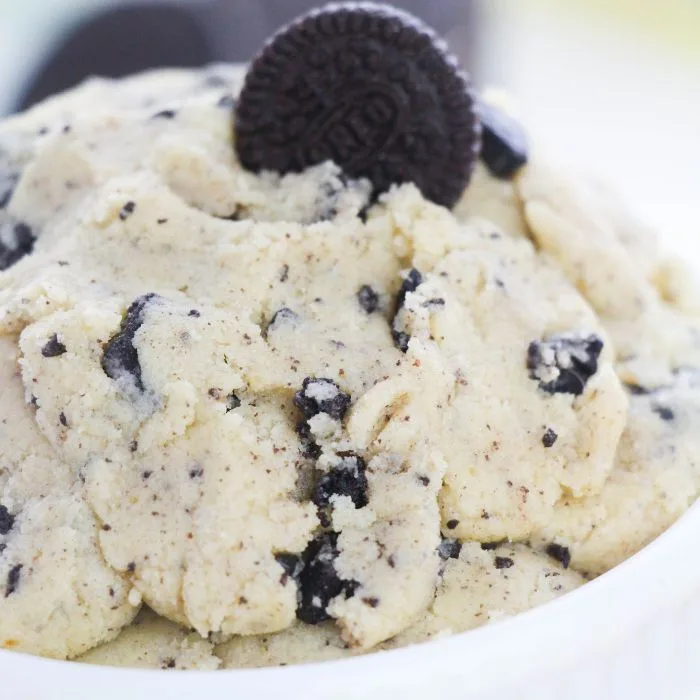 close-up of vanilla-flavored dough with crushed oreo cookies and a full cookie on top