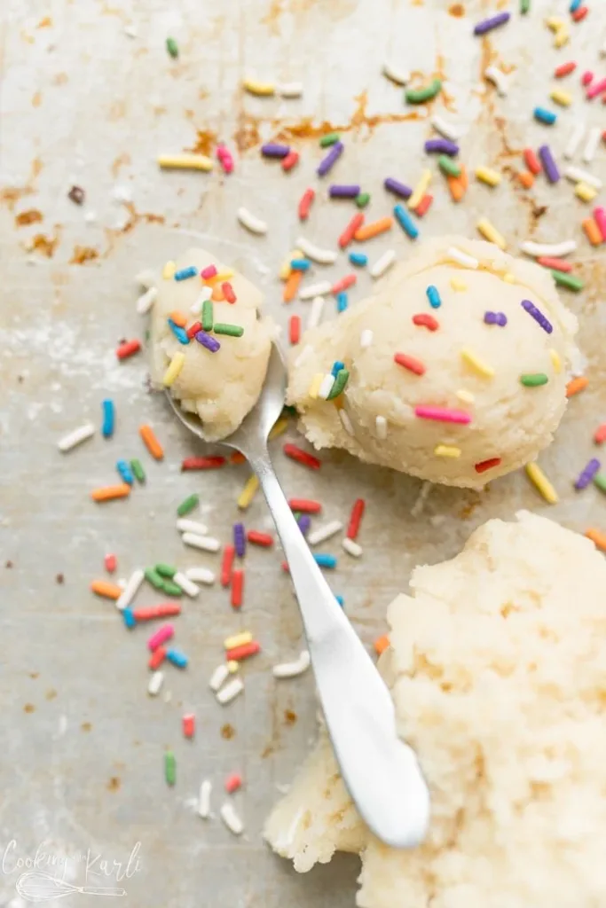 scoop of sugar cookie dough with rainbow sprinkles on a baking sheet
