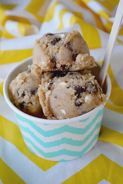 a cup filled with scoops of edible s'mores cookie dough featuring chocolate chunks and marshmallow pieces